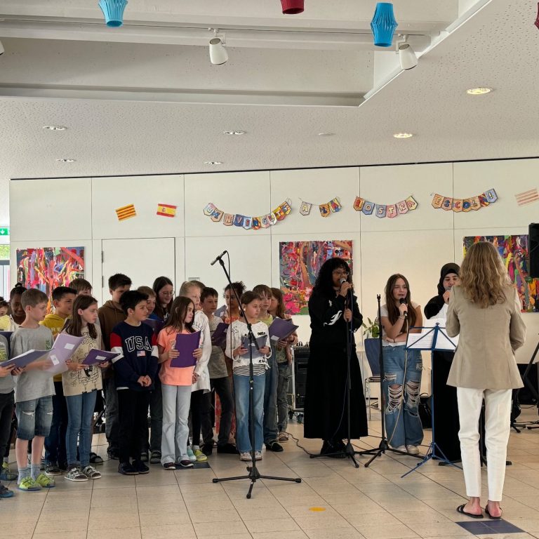 Bandklasse Impression Kinderchor singt in einem hellen Raum, umgeben von kunterbunten Kunstwerken.