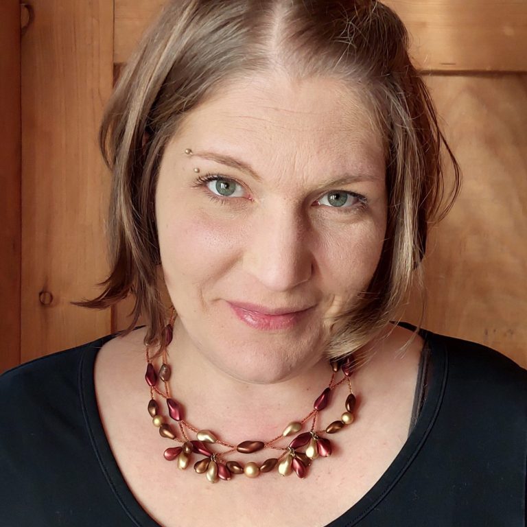 Frau mit mittellangem Haar, trägt eine elegante Halskette und schaut freundlich.