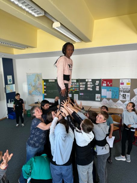 Schüler bilden einen Menschenpyramide, eine Person steht oben auf den anderen.